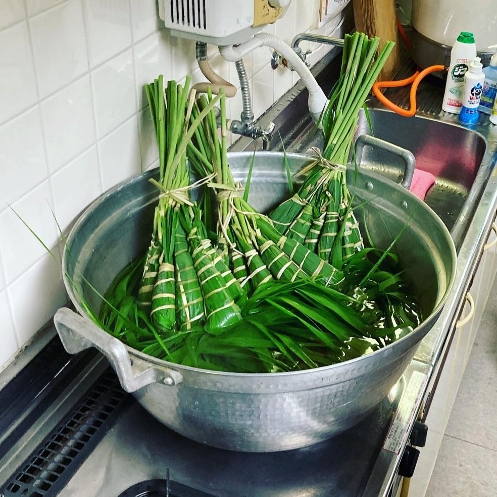 ガマの紐で結ばれたちまきの束を大鍋で茹でる準備をする様子