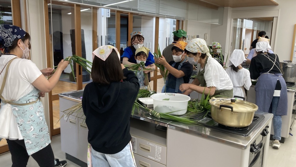 ガマの紐でちまきを結ぶ体験参加者