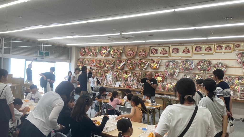 縁起物づくりについて説明する五代目社長と参加者