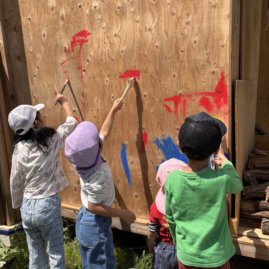 小屋の壁に色を塗る子どもたち