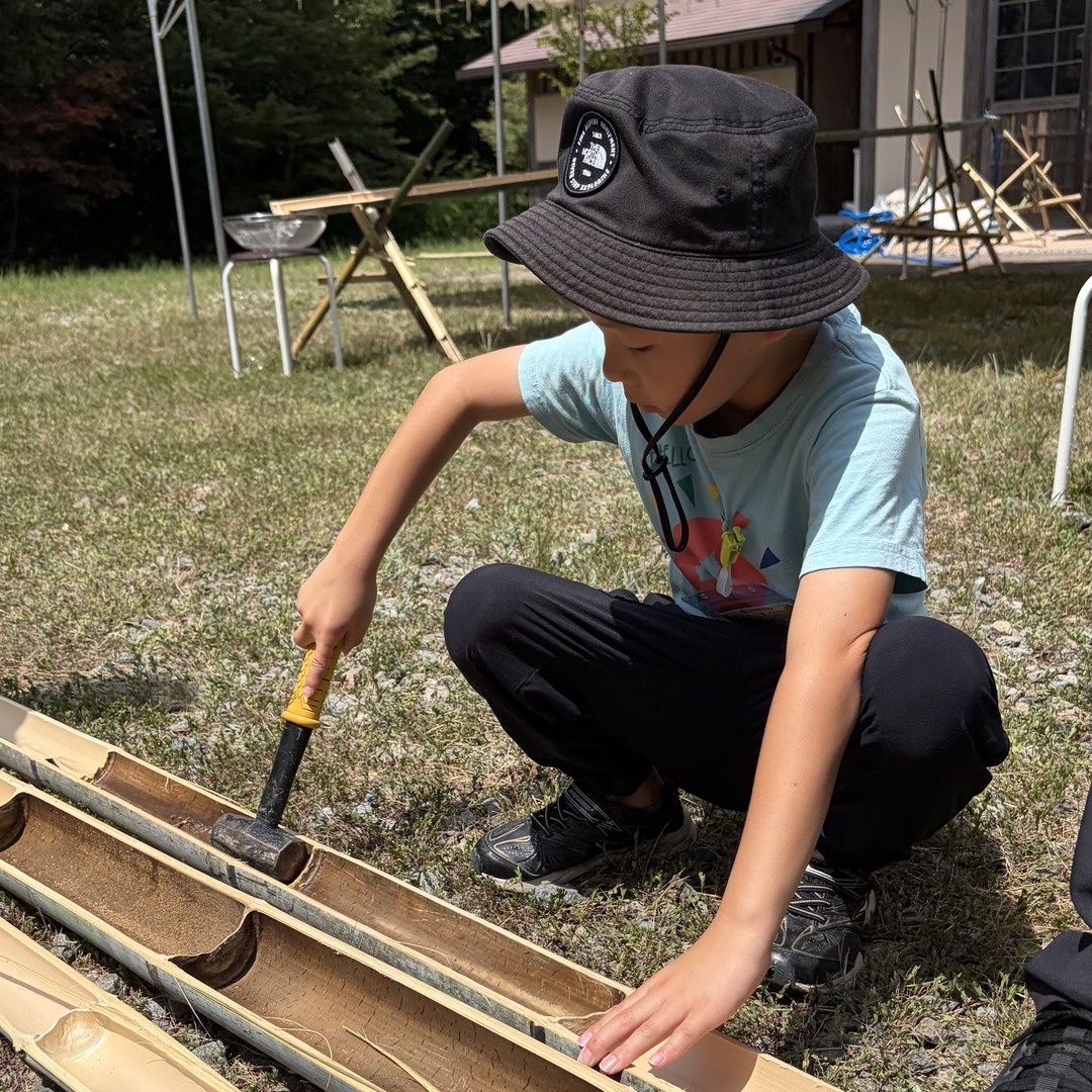 金づちで竹の節を落とす作業に挑戦する男の子