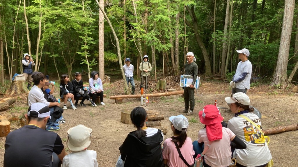 宝の森の広場で橋本成隆さんの説明を聞く親子
