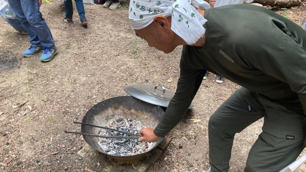 炭窯の中の小枝を火ばさみで整える橋本成隆さん