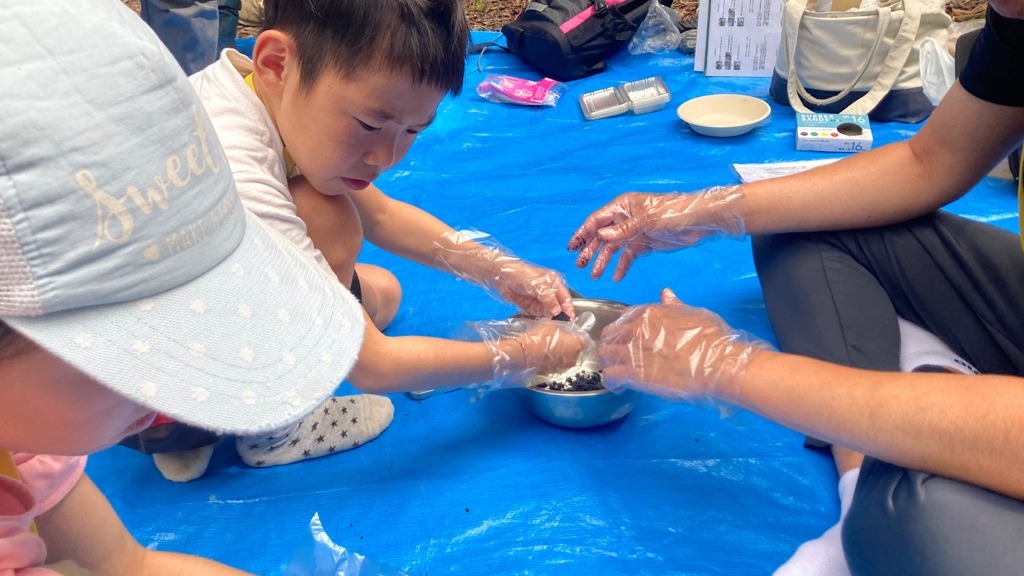 ボウルの中の炭を手で押し固める子どもたち