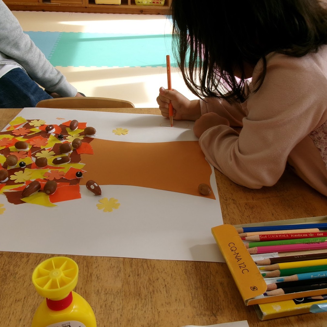 机に向かって秋のクラフト作品を作る子ども