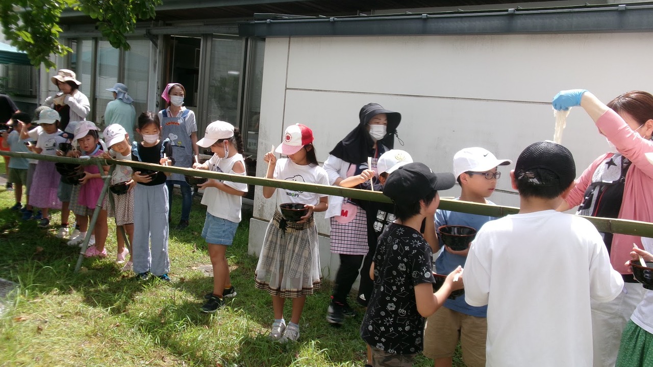 竹で作った流しそうめん台を囲む子どもたち