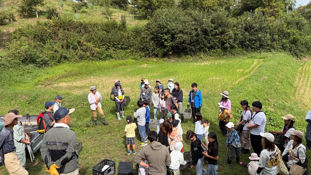 栗園の広場で輪になり栗拾いの説明を聞く参加者