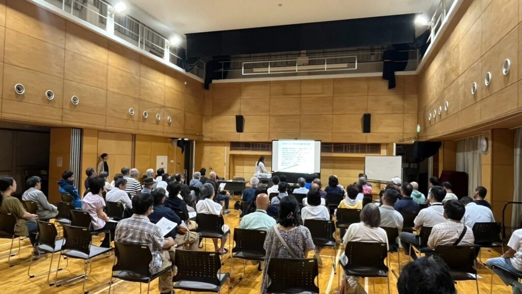 西谷会館屋内活動室に多くの参加者が集まり、講師の話に耳を傾けている。
