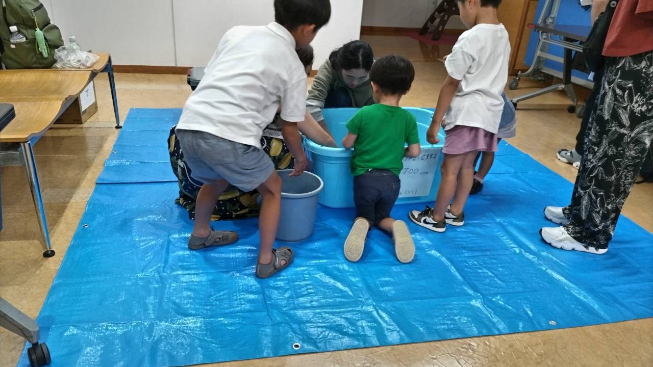 水槽をのぞき込んでオオサンショウウオを観察する子どもたち
